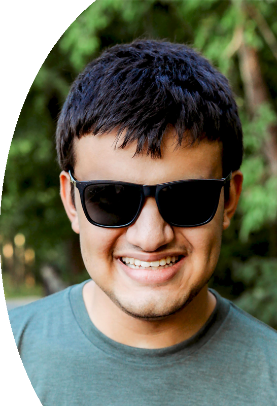 Allan Wylie is a young man with short, dark hair and light brown skin. He is outdoors, wearing black-framed sunglasses and smiling.