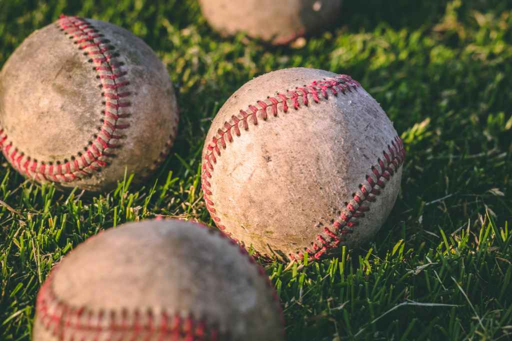Close-up view of worn baseballs laying in a close-cut grass area