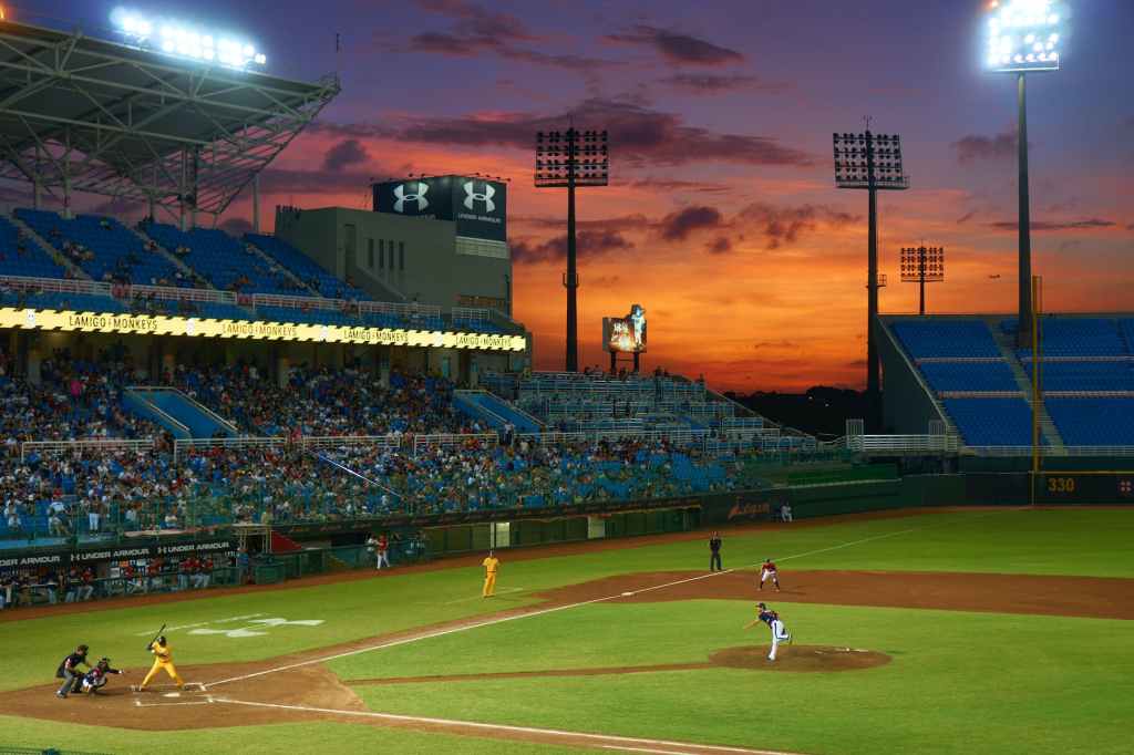 View of gameplay at a baseball stadium while the sun sets in the background.