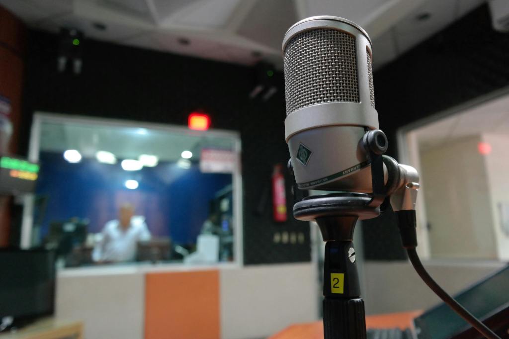 Close-up of a microphone with a production studio in the background