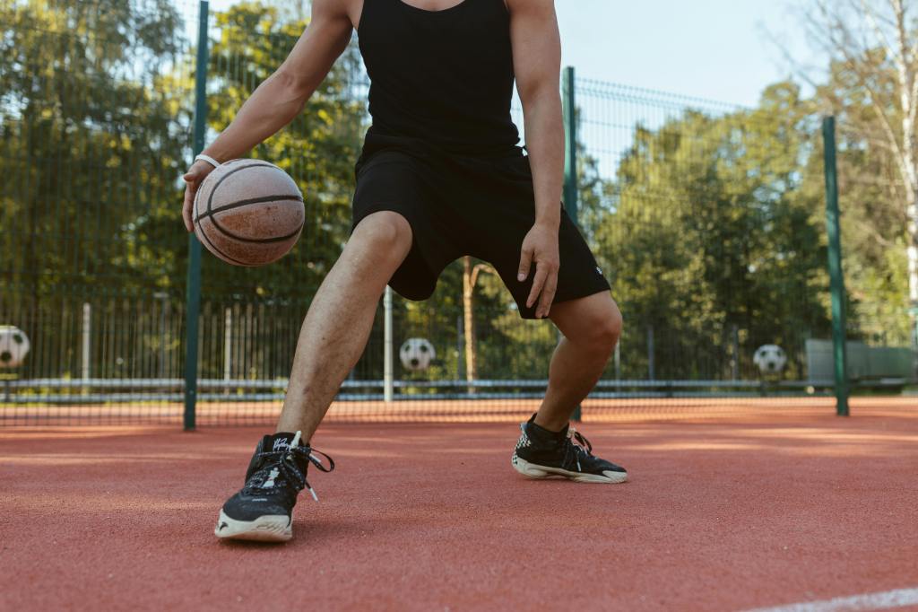 A man dribbles a basketball at an outdoor court.